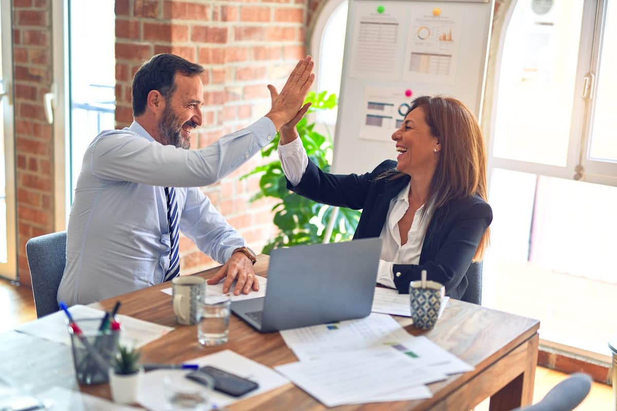 Two colleagues celebrating a successful project at their desk